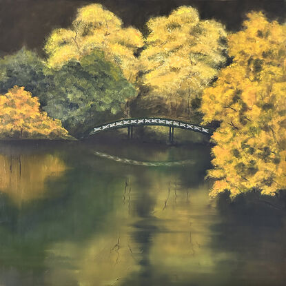 Golden tones of autumn and footbridge reflected in still waters of lake.