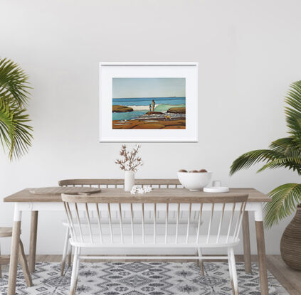 Two figures, a mum and daughter, stand on the rocks watching the turquoise waves at the beach. A small dog runs past and two seagulls look on. The cobalt blue and turquoise of the sea are set against the warm sienna of the rocks.