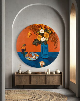 A circular still life  painting in rich orange and contrasting blue?  depicting flowers, rainbow lorikeet birds, a teacup and a small plate with ornaments. 