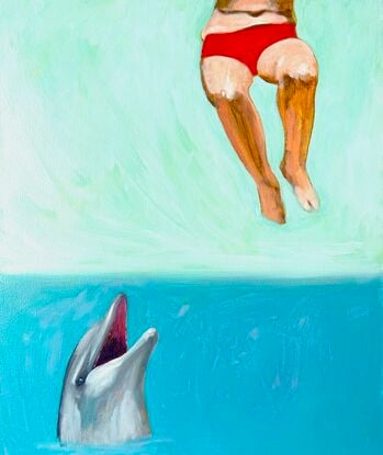 A dolphin looks up from the water as the lower half of a woman in a bikini hangs in the air.