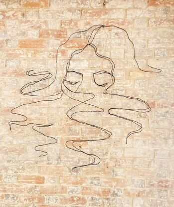 A continuous line drawing sculpture,  made with wire, of a woman with her face half submerged into water. Curls of hair floating around her. 