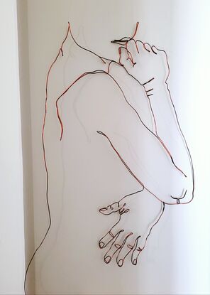 A wire sculpture. Single line drawing of a nude female looking over her shoulder