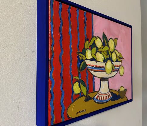 a modernist still life with bright red and pink background. A white pedestal bowl of lemons sits on a rounded brown table