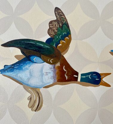 Three ceramic mallard ducks flying across a beige patterned wallpapered wall