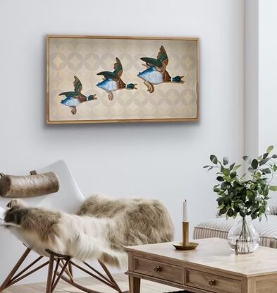 Three ceramic mallard ducks flying across a beige patterned wallpapered wall