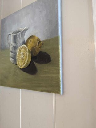 Milk jug and lemons on green 