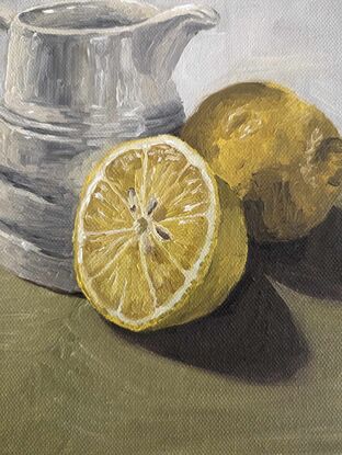 Milk jug and lemons on green 