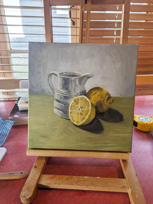 Milk jug and lemons on green 