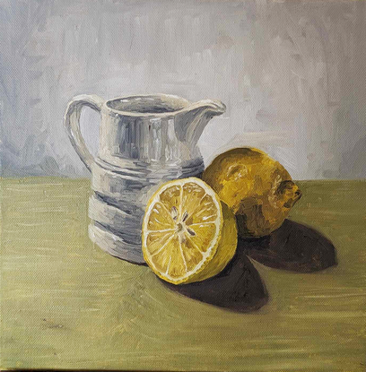 Milk jug and lemons on green 