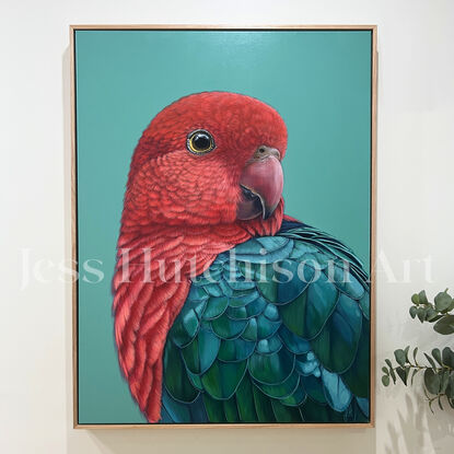 A portrait of a male King Parrot looking over his shoulder. His plumage is vibrant red and greens/ blues and the background is a vibrant jade green.