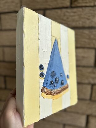 Slice of blueberry cheesecake on yellow striped tablecloth