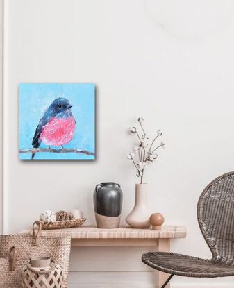 Textured oil painting of a native Australian bird, the Rose Robin, perched on a twig. The bird has a grey head and back feathers and a rose pink feathered chest. The background is sky blue.