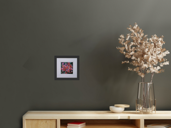 a cluster of flowering pink gumnuts amidst an array of green leaves beautifully presented in a simple black frame with white double mat