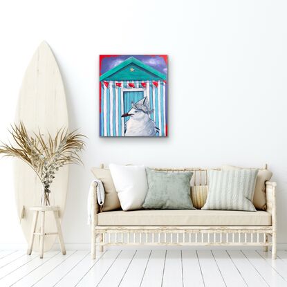 Seagull wearing a newspaper hat in front of a beach hut.