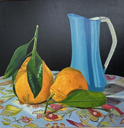 Bright orange Tangelo Fruit, large blue jug showing reflections , on a floral patterned  tablecloth, 