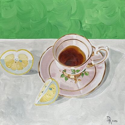 A pink tea cup filled with tea on a white surface.  There are lemon wedges within the composition. Background is green. 