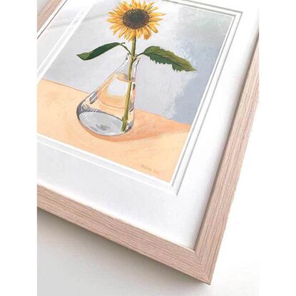 One sunflower in glass vase on peach and blue background