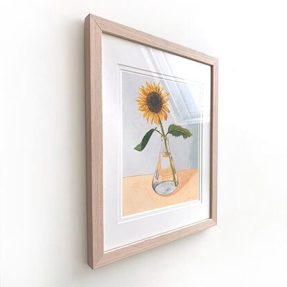 One sunflower in glass vase on peach and blue background