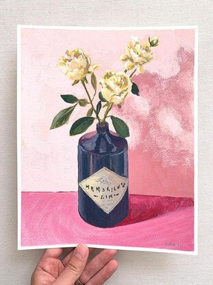 White rose flowers in black gin bottle on pink background