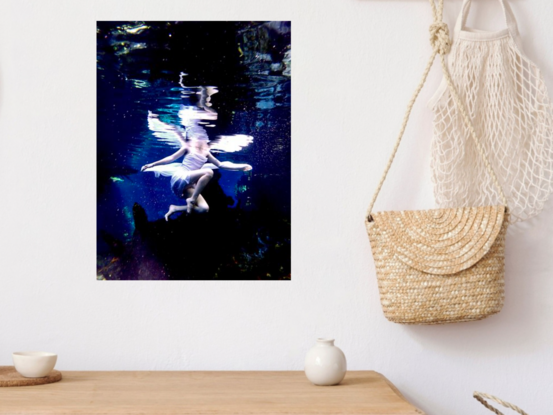 Young woman sitting upon a log underwater in white dress with fairy wings - patiently waiting.