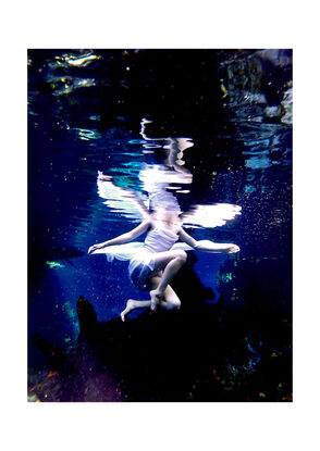 Young woman sitting upon a log underwater in white dress with fairy wings - patiently waiting.