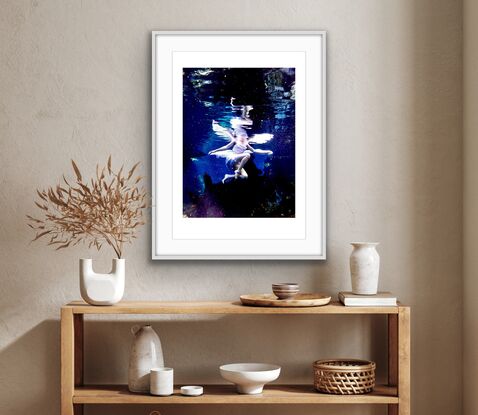 Young woman sitting upon a log underwater in white dress with fairy wings - patiently waiting.