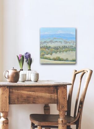 A painting of an Australian country landscape with distant rolling hills, gum trees, farm houses and grazing sheep.