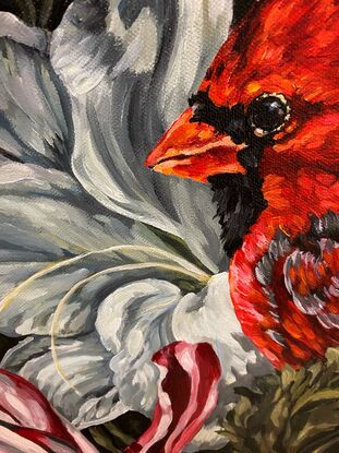 Red cardinal sits among flowers and vines with white  flowers and blue flower and striped red and white tulip on black and grey patterned ground 