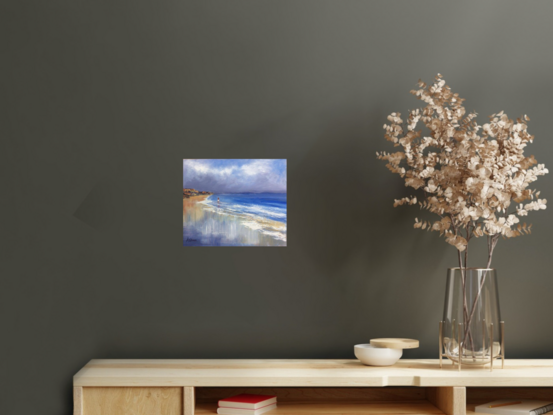 Seascape with distant headland and gentle waves reaching into the shore.  There is a small figure in the distance walking in the shallow water.