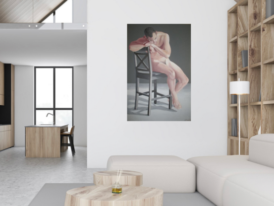 3/4 view of nude man sitting on chair, cheek resting on hands holding back of chair