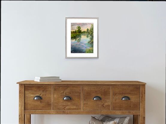 Trees and grasses reflecting in a large blue waterway with pinky purple clouds. 