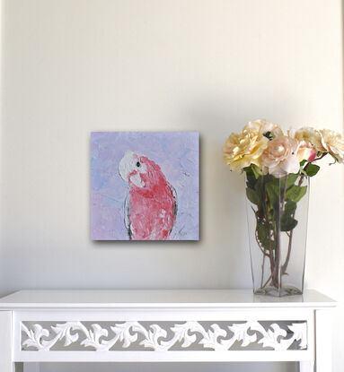 A textured portrait painting of a pink, grey and white galah cockatoo is depicted against a soft lavender background.