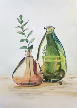 2 glass bottles with a stem of leaves.