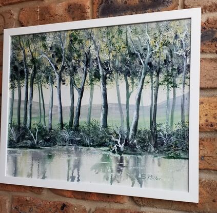 Trees & water with a green tone overall. Framed in white timber.  No glass needed