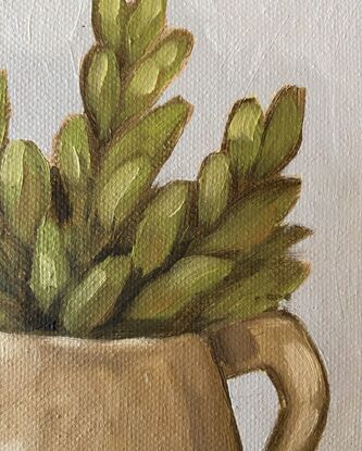 Green foliage in a mustard jug on a neutral background.