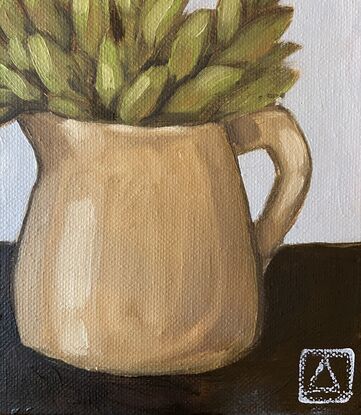 Green foliage in a mustard jug on a neutral background.