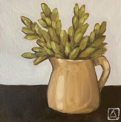 Green foliage in a mustard jug on a neutral background.