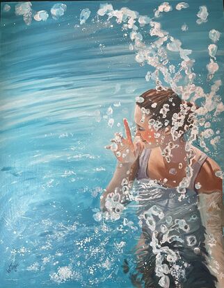 A beautiful woman stands waist deep in a blue swimming pool, as she raises her hand water drops fly up creating a sparkling display.