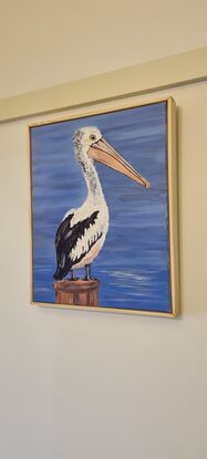 A pelican stands on a post overlooking the water.