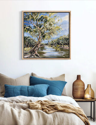 A swaying gumtree leans across the Murray River. The blue sky is reflected in the water. 