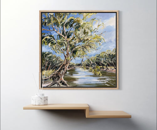 A swaying gumtree leans across the Murray River. The blue sky is reflected in the water. 