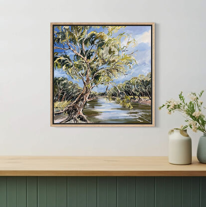 A swaying gumtree leans across the Murray River. The blue sky is reflected in the water. 