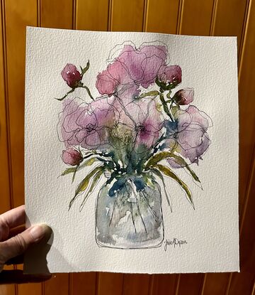 A bouquet of soft pastel roses and buds in pink and mauve in a glass vase