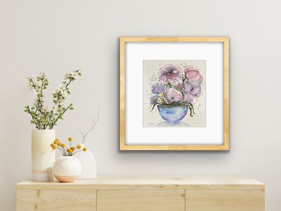 A bouquet of soft pastel flowers in pink and mauve in a round blue vase