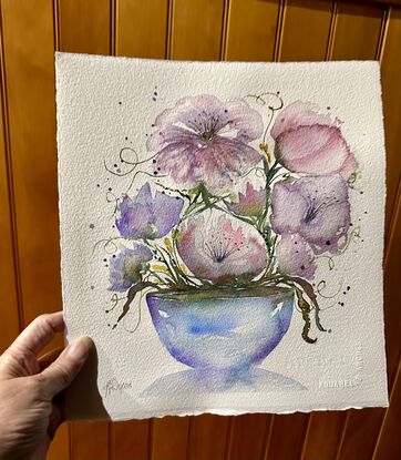 A bouquet of soft pastel flowers in pink and mauve in a round blue vase