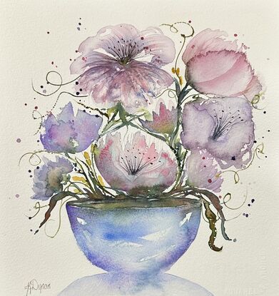 A bouquet of soft pastel flowers in pink and mauve in a round blue vase