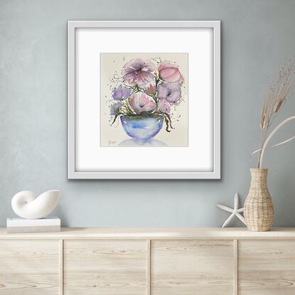 A bouquet of soft pastel flowers in pink and mauve in a round blue vase