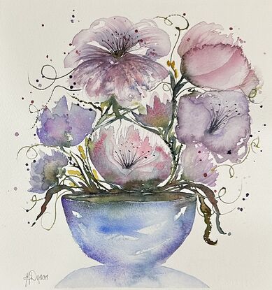 A bouquet of soft pastel flowers in pink and mauve in a round blue vase