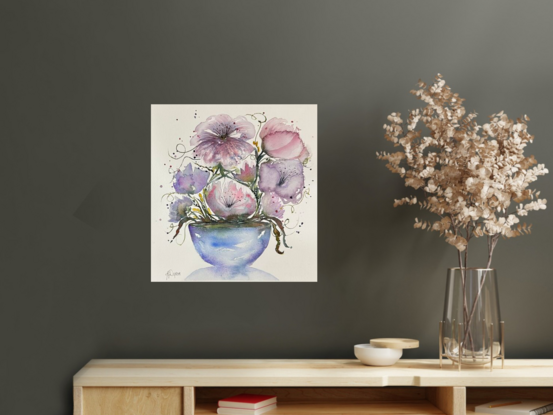 A bouquet of soft pastel flowers in pink and mauve in a round blue vase