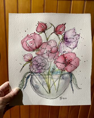 A bouquet of soft pastel flowers in pink and mauve in a round glass vase